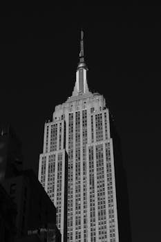 A dramatic black and white photograph of the iconic Empire State Building in New York City.